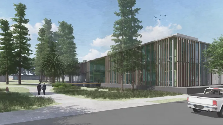 A building with a walking path lined with trees and grass.