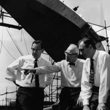 A group of men fixing a tie.