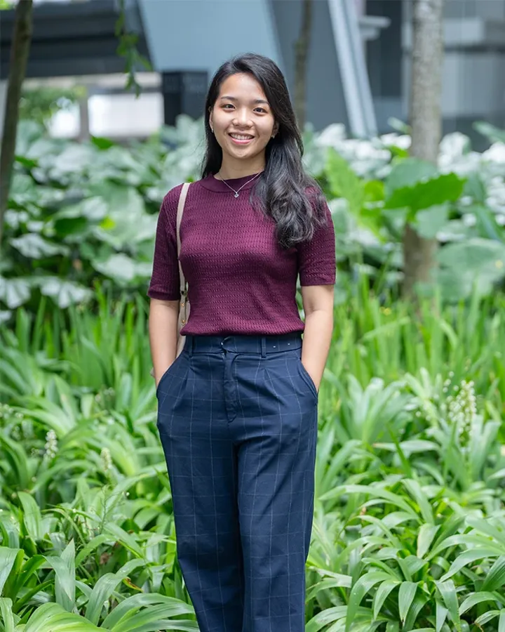 A girl smiling in front of greenery