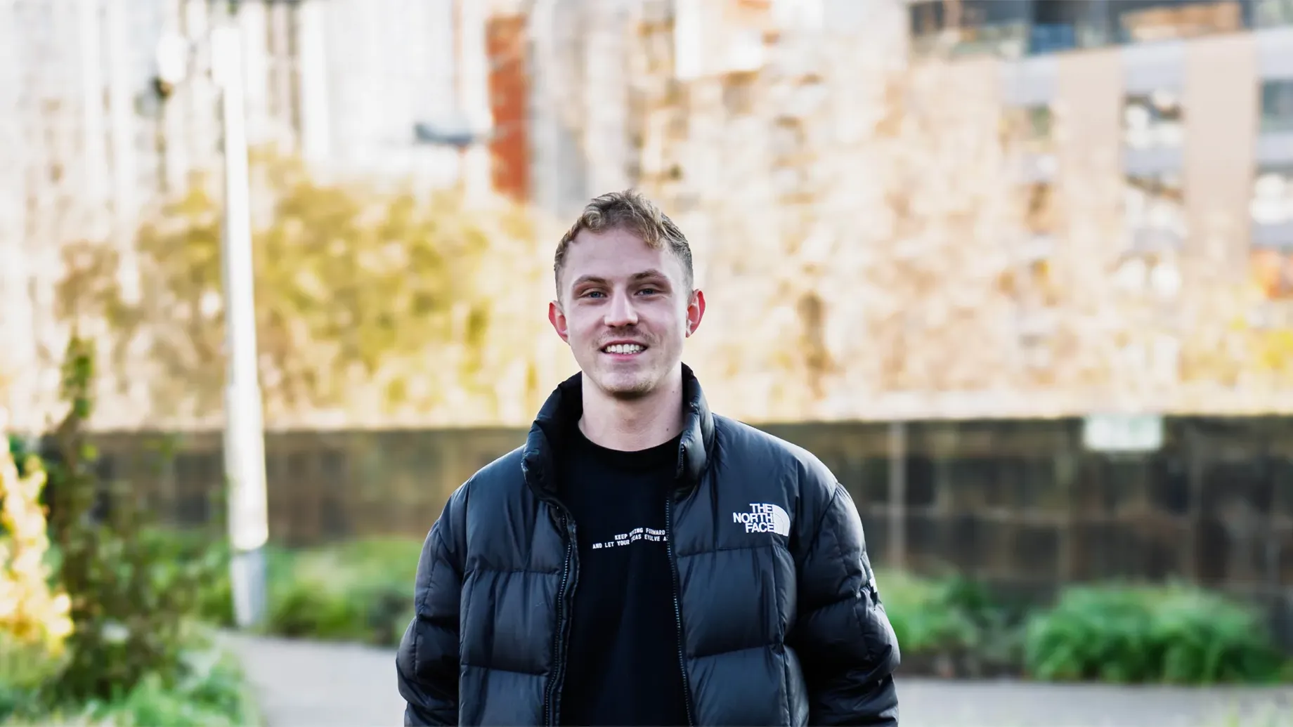 A boy in a black jacket smiling at the camera