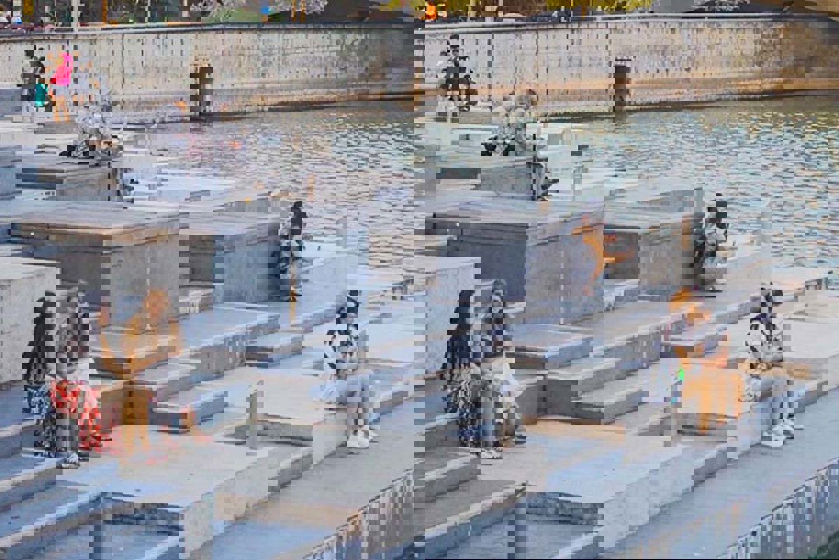 Women sitting by a body of water in a city