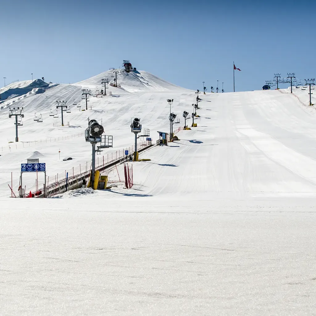 A ski lift going up a snowy hill.