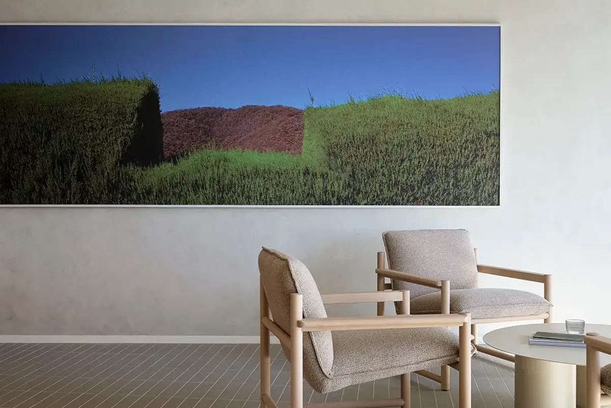 A table and chairs in front of a wall with a green landscape.