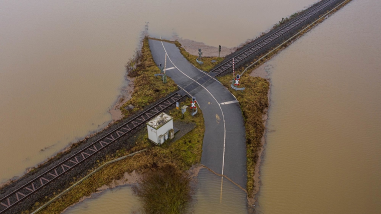 Aerial view of a flooded road and railway crossing the road