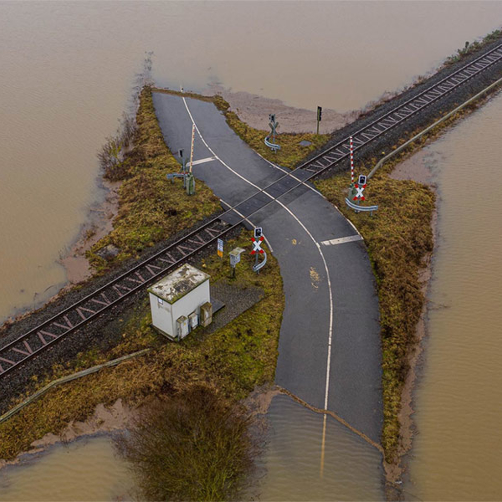 Aerial view of a flooded road and railway crossing the road