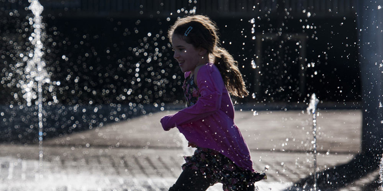 Child running through fountains