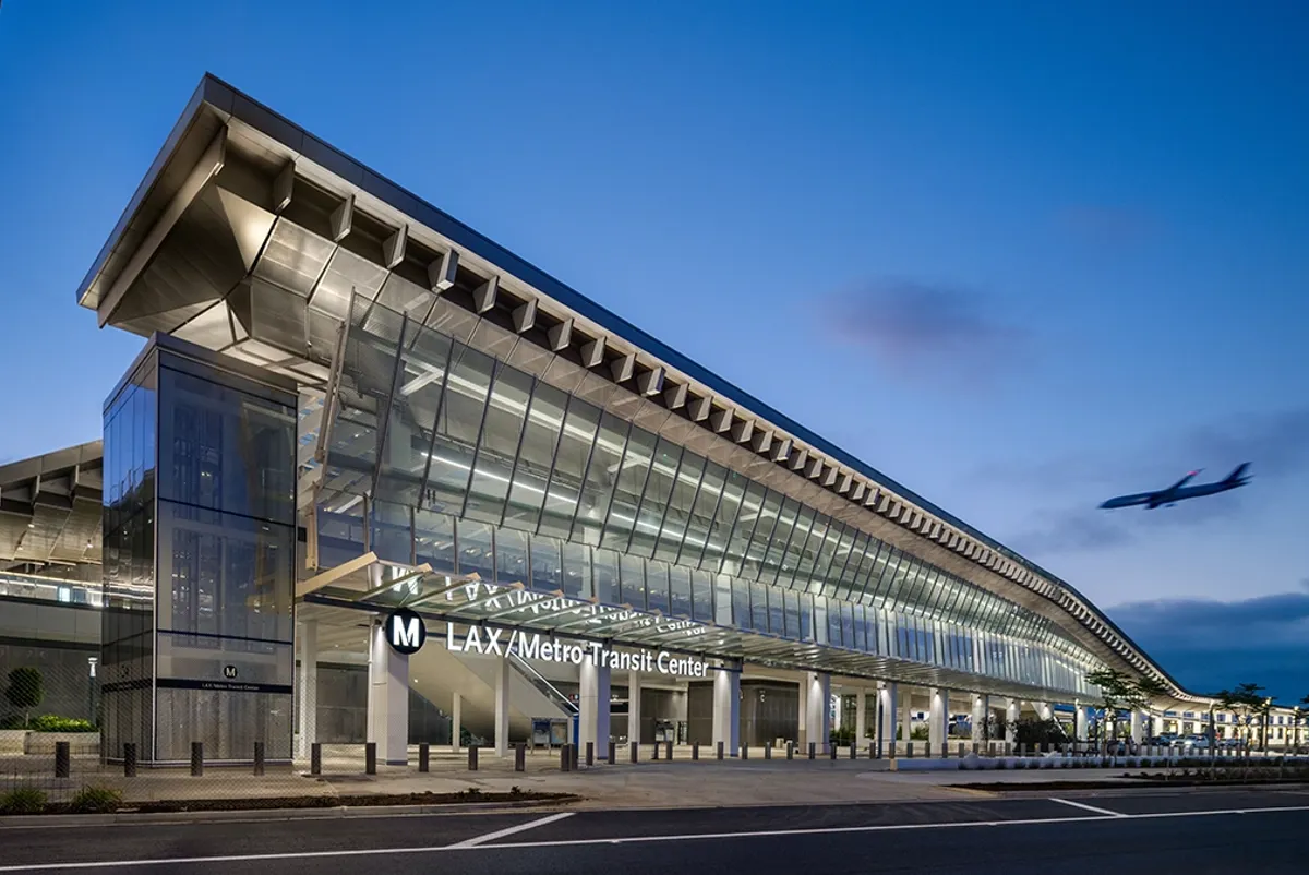 A large transit center at the airport with a plane flying by