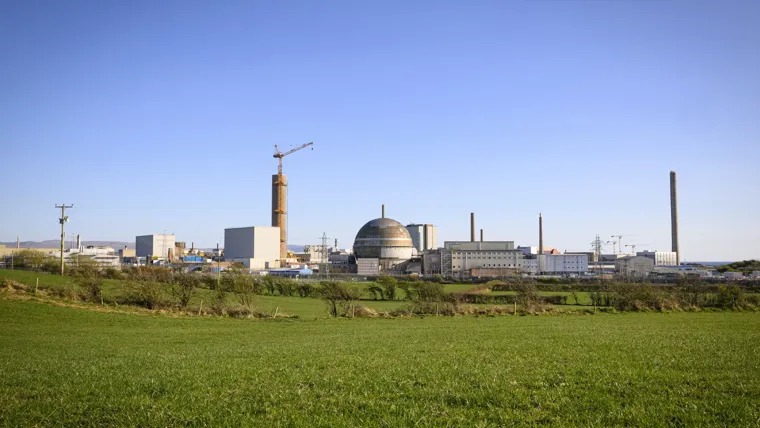 A large field with a factory in the background.