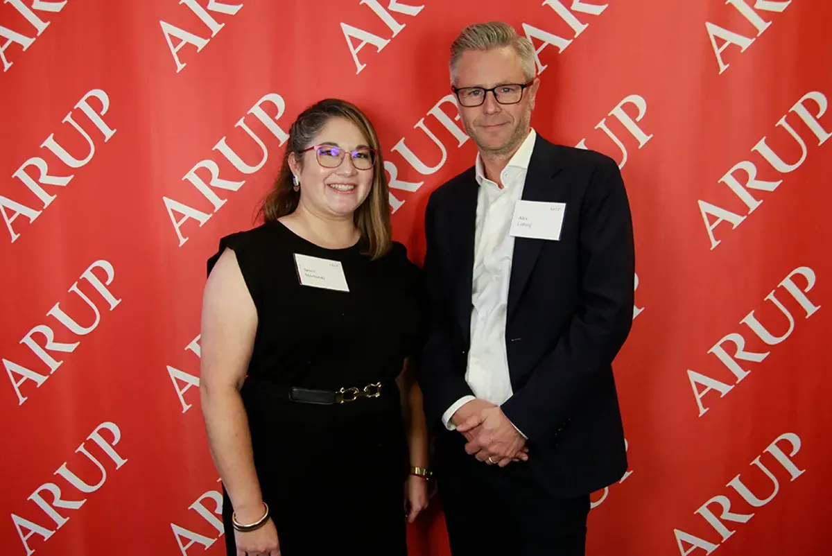 A man and a woman standing in front of a red wall.