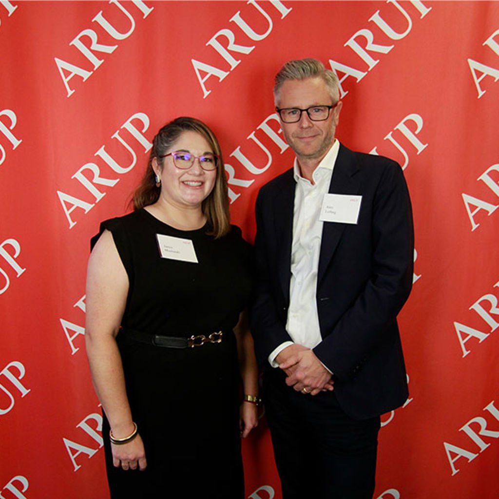 A man and woman standing in front of a red wall.