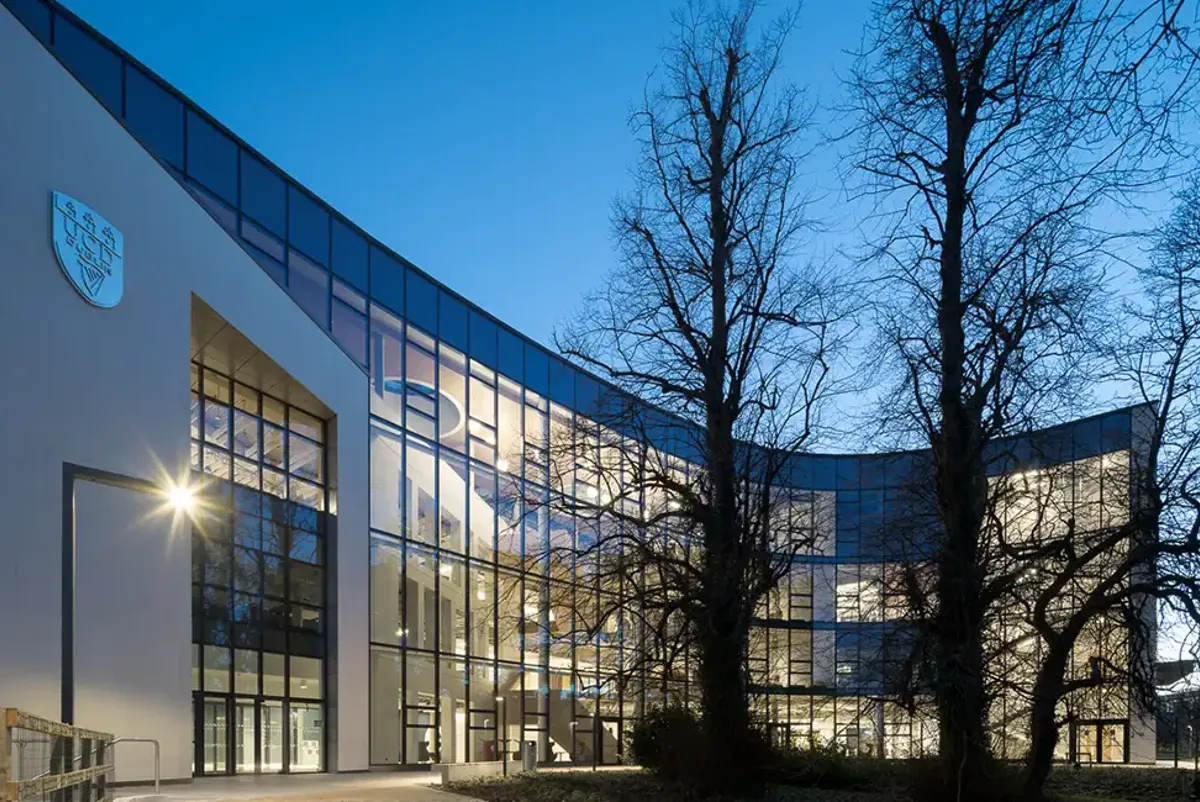 Night-time view of the O'Connor Centre for Learning, showing the University College Dublin crest and trees outside.