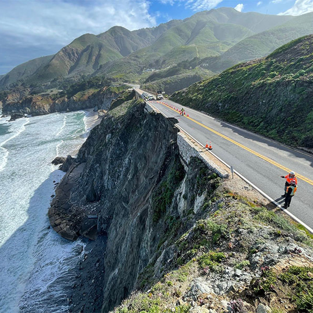 A person on a road by a body of water.