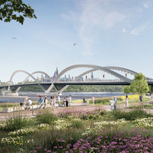 A group of people walking on a path by a bridge
