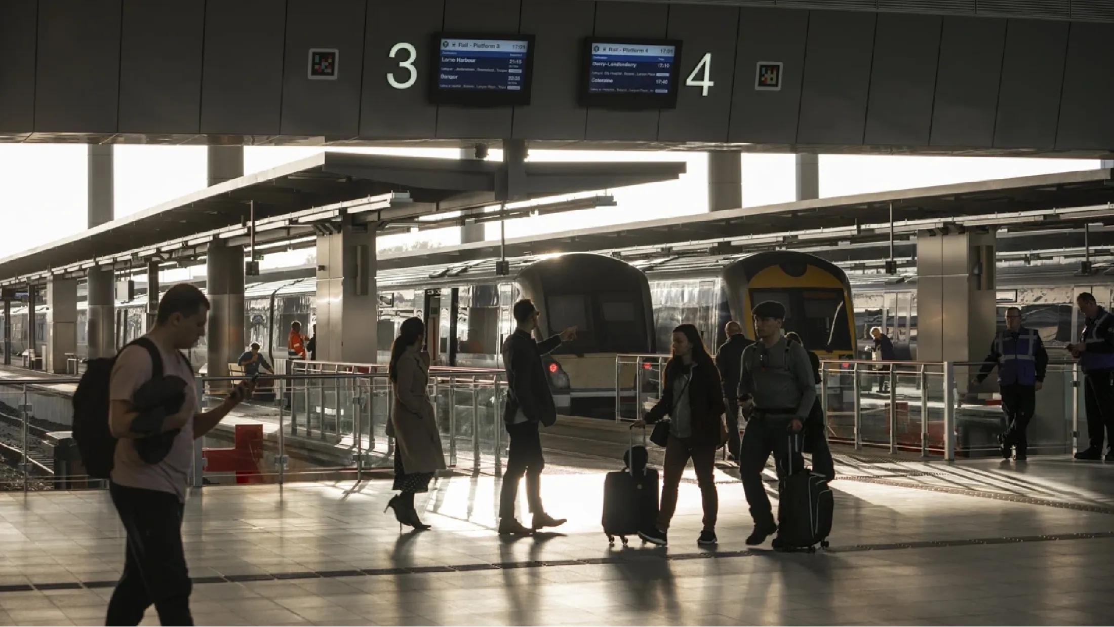 Trains docked at platform 3 and 4, with travellers passing by