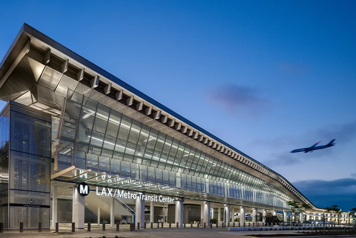 A large transit center with a plane flying by at dusk