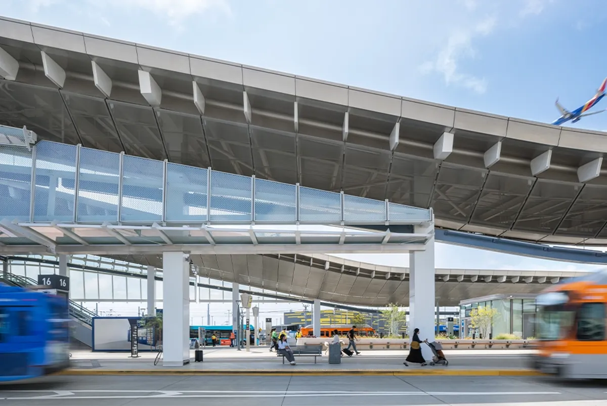 A large transit center with buses passing and a plane flying over it