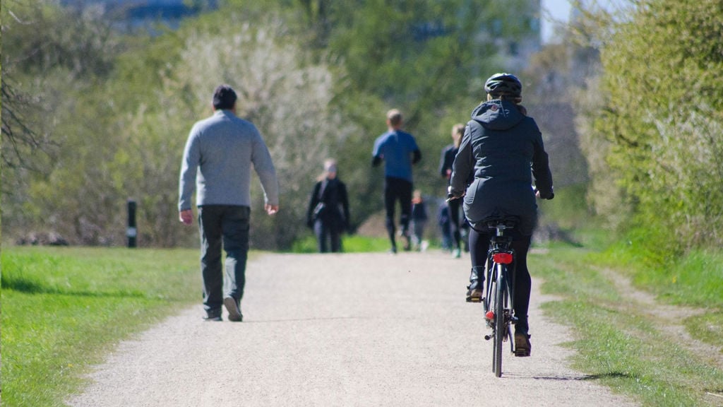 A person cycling and people walking on a path