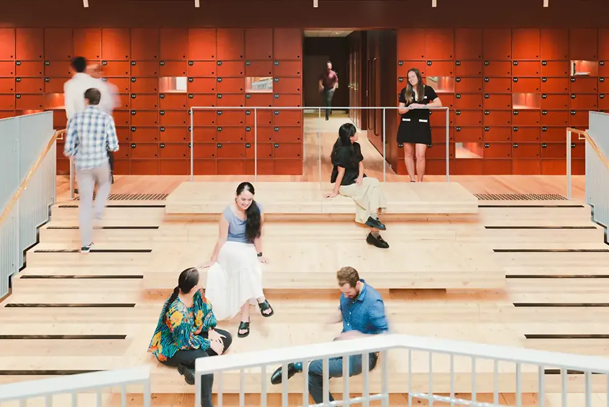 A group of people sitting on stairs within a modern workplace 