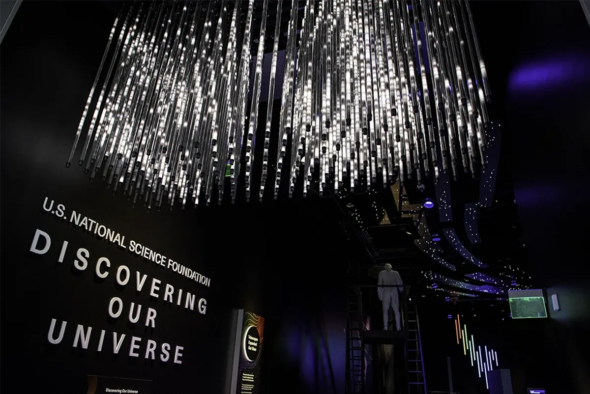 Detailed ceiling light system made from hanging rods in a spiral shape in a dark exhibit.