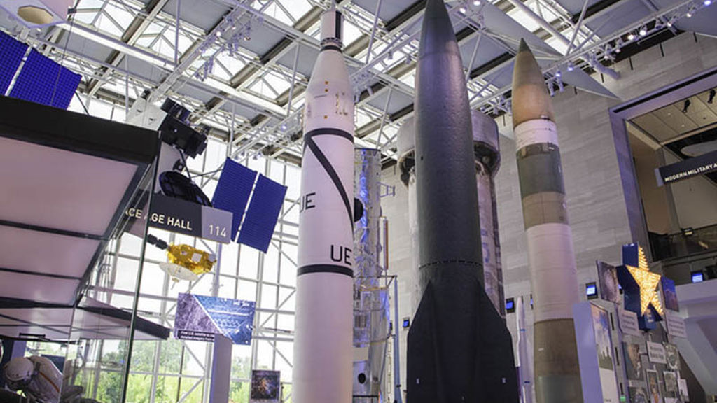 Space artifacts in naturally well-lit room with floor to ceiling windows.