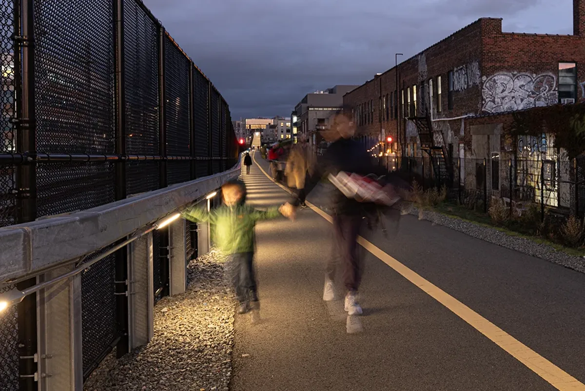 A person and a child walking on a community path at dusk
