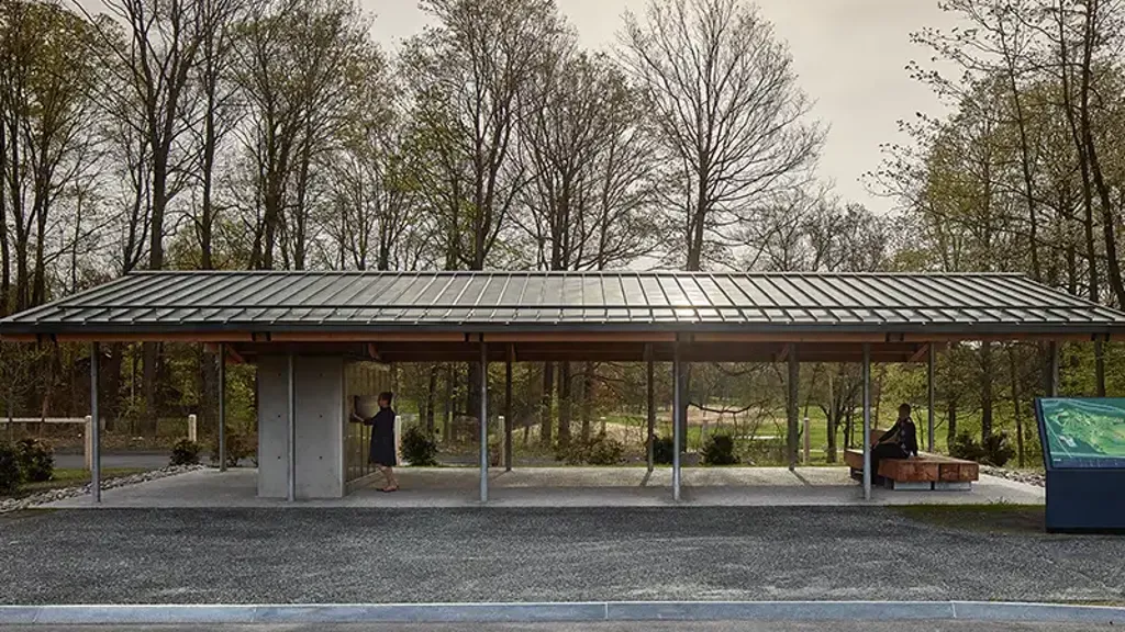 A covered area with a person sitting on a bench.