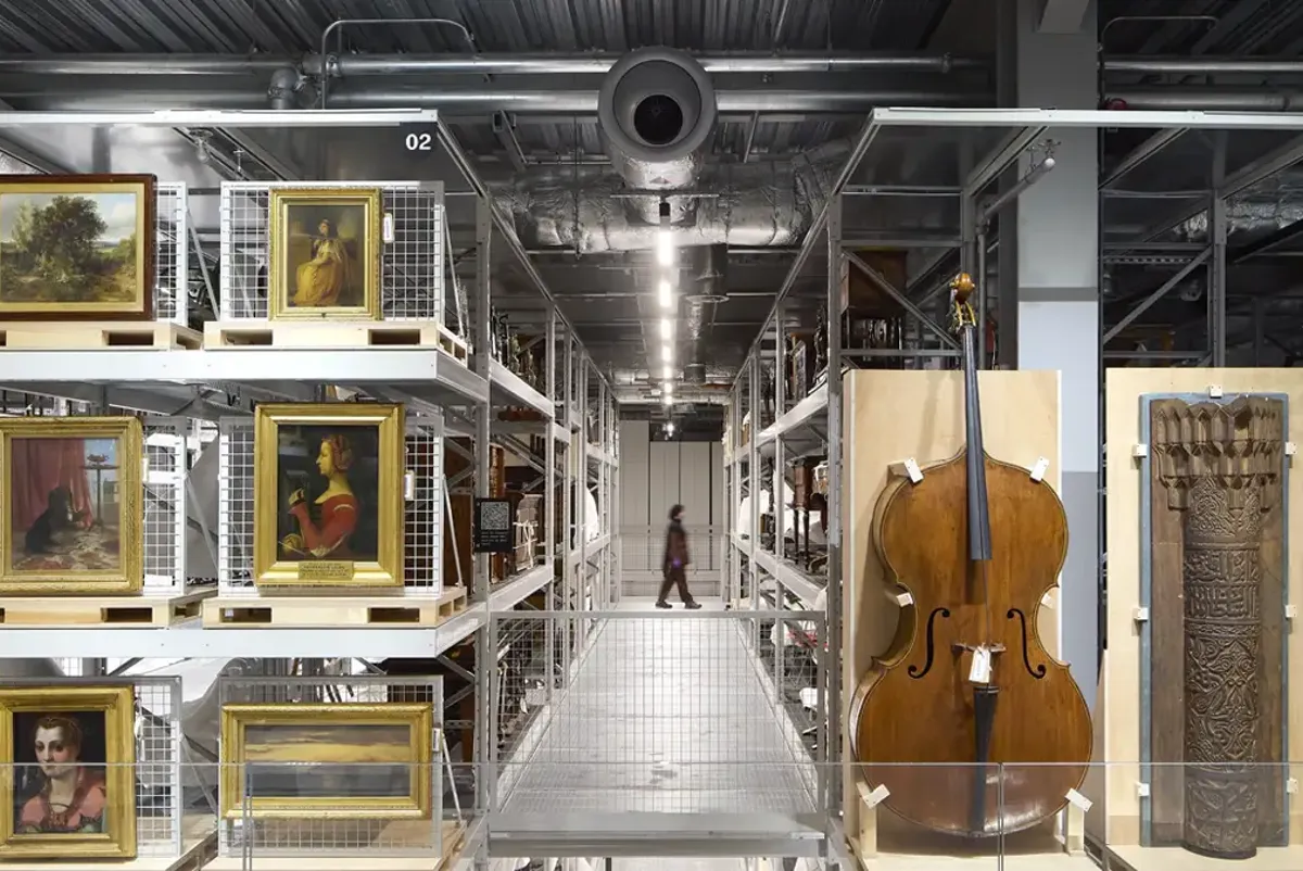 A violin in a room with pictures and a stage with a person standing.